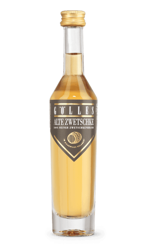 Gölles Zwetschkenbrand Alte Zwetschke in Klarglasflasche mit schwarzem Dreiecksetikett und goldenem Verschluss.