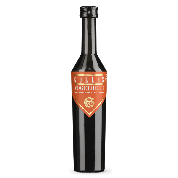 Gölles Vogelbeerbrand in dunkler Flasche mit orangefarbenem Etikett, goldener Schrift und Emblem.