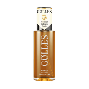 Gölles Weißer Balsamessig, goldgelb, in hoher Glasflasche mit weiß-schwarz-goldenem Etikett.