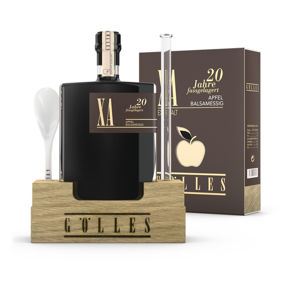 Gölles XA Apfel Balsamessig in eckiger Flasche im Holzständer mit Porzellanlöffel, Pipette und Schachtel.
