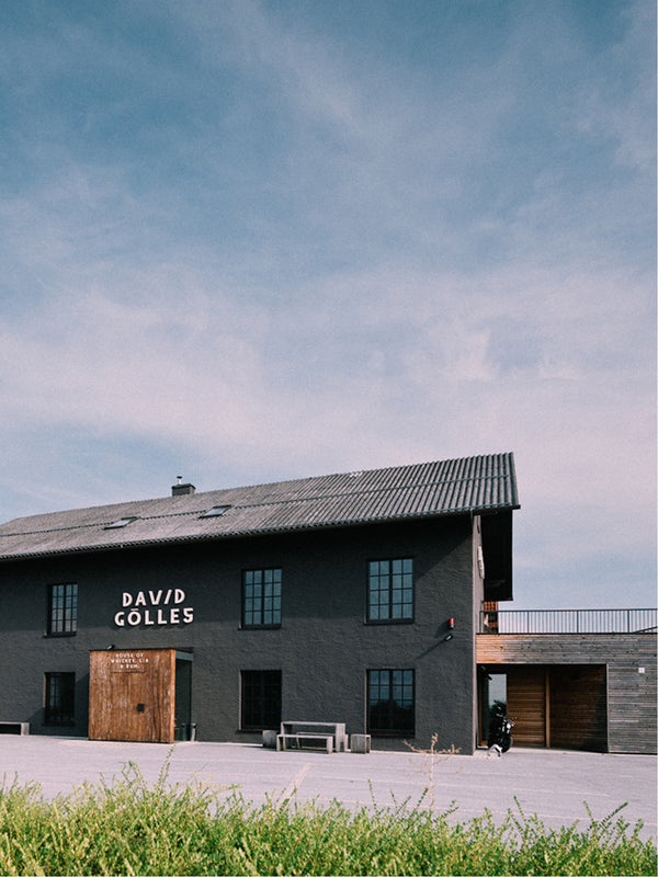 Dunkelgraues Giebelgebäude mit Holzeingang und Schild DAVID GÖLLES house of whiskey, gin & rum.